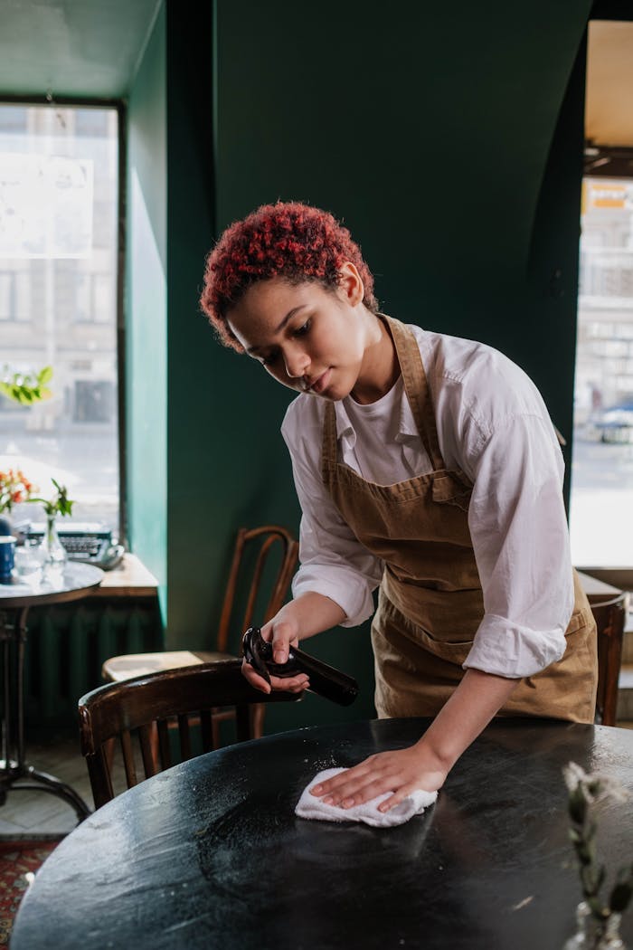 Young waitress cleans a table in a cozy café, capturing the essence of service and hospitality.